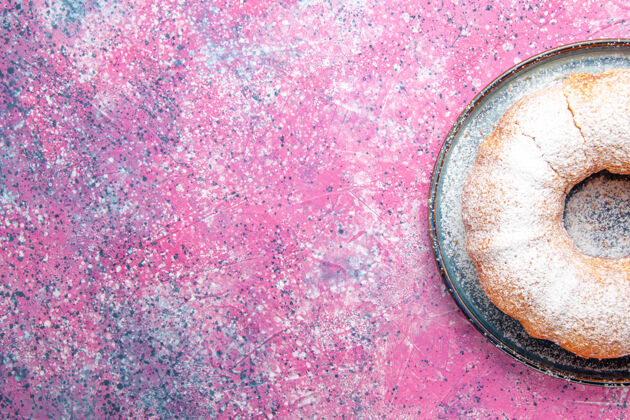 美味粉红色桌子上形成的糖粉蛋糕圆的俯视图饼干墙壁美味