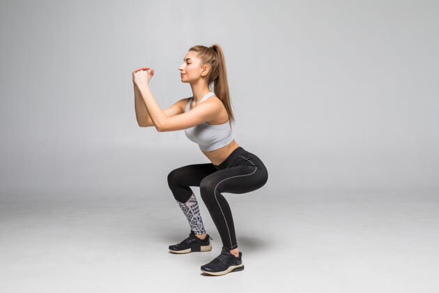 有氧运动运动的女人做蹲肌肉健康的女人在军事运动服隔离白墙健身和健康的生活方式的概念人热身力量
