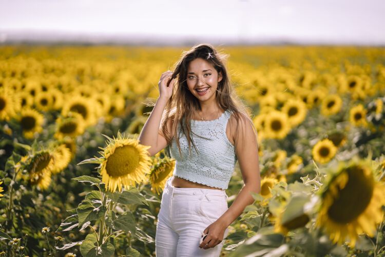 美丽在阳光明媚的日子里 一位白人年轻女性在向日葵的田野里摆姿势的水平镜头明亮可爱开花