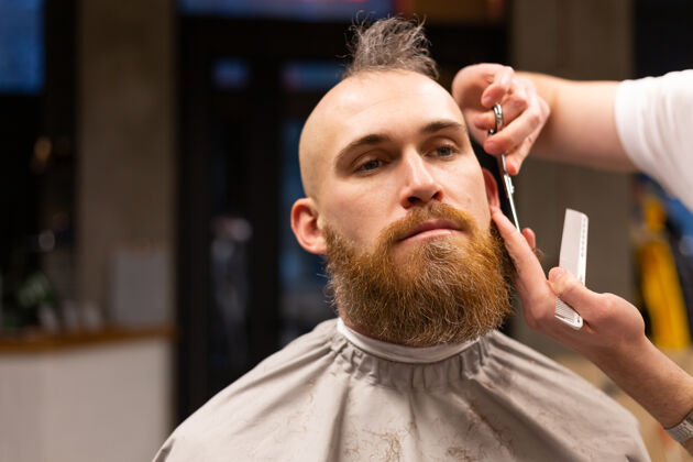 工作在理发店剪胡子的欧洲野蛮人头发剃须刀家伙
