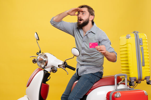 年轻人旅游概念与年轻的情绪集中胡须男子坐在摩托车和持有银行卡上的黄色摩托车人旅行
