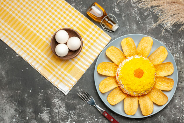 桌子右侧沙拉顶视图 黄色餐巾纸油瓶叉子小麦和一碗鸡蛋放在深灰色的桌子上餐巾沙拉叉子
