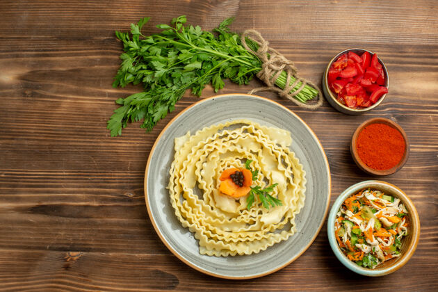 午餐顶视图生面团设计面团与绿色和调味品在棕色背景面团食品蔬菜盘子顶部装饰