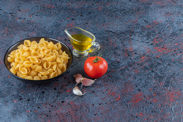 干的把生面食放在一个玻璃碗里 盛上新鲜的红色番茄和大蒜未烹调的顶视图午餐