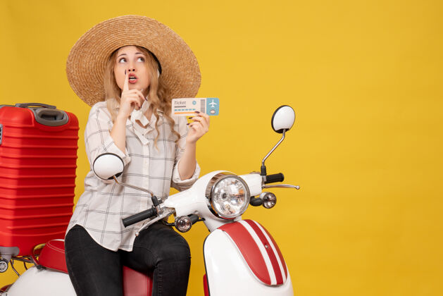 顶俯视图上的焦点年轻女子戴着帽子 坐在摩托车上 拿着车票仰望黄色剪影团队坐