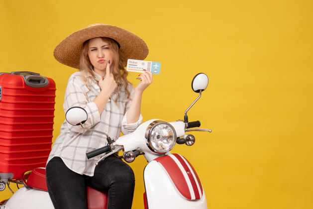 团队顶视图好奇的年轻女子戴着帽子 坐在摩托车上 手里拿着黄色的车票年轻女子摩托车人