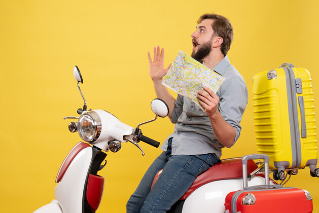 微笑旅游概念与年轻紧张的胡须男子坐在摩托车上 并显示地图上的黄色年轻人自行车旅游