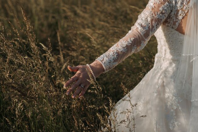 女性新娘穿着漂亮的婚纱和珍珠手镯走在麦田里美女浪漫庆典