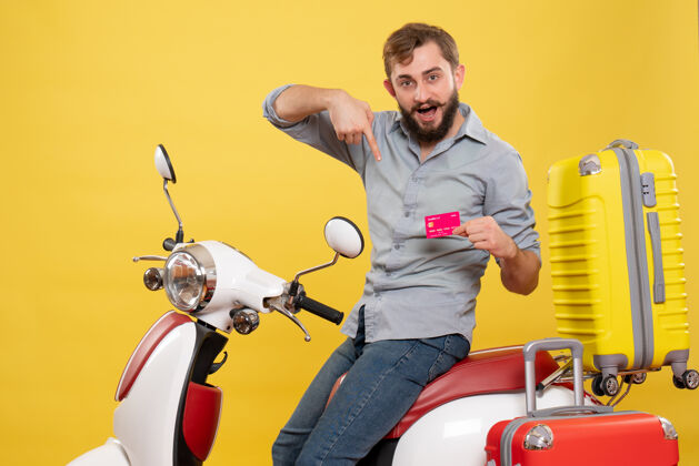 自行车旅游概念 年轻自信的胡须男子坐在摩托车上指着黄色的银行卡微笑人年轻人