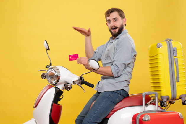 年轻人旅游概念与年轻情绪自信胡须男子坐在摩托车上持银行卡黄色自行车传送带旅行