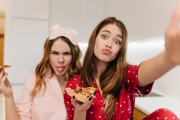 披萨可爱的年轻女子吃比萨饼 到处闲逛积极的姐妹们玩得开心 享受最喜欢的快餐娱乐小吃美味