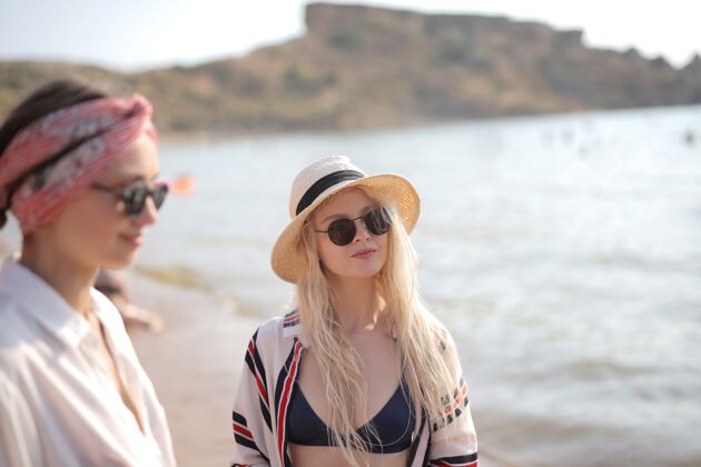 成功海滩上两个戴眼镜的年轻女子的选择性聚焦镜头沟通沙滩女性