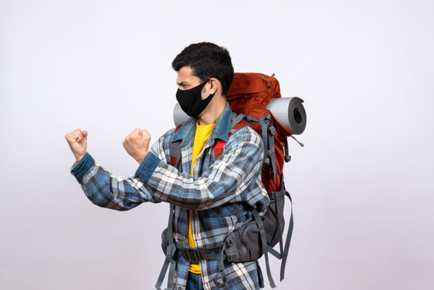 时尚正面图愤怒的年轻徒步旅行者背着背包和面具准备战斗背包设备建筑