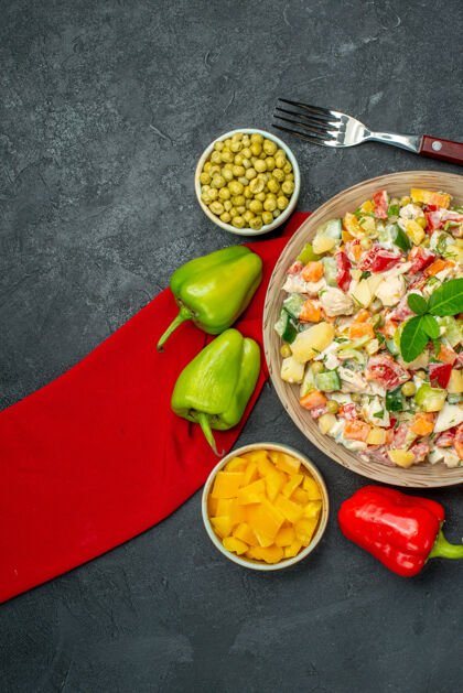 胡椒红色餐巾上的蔬菜沙拉俯视图 深灰色背景上的蔬菜和叉子在一边晚餐食物盘子