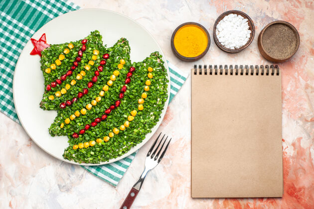 新的顶视图美味的绿色沙拉在新年树形状与调味品上的灯光背景餐光形状