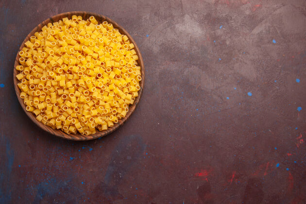 生的顶视图黄色意大利面食生面团在深色桌子上形成面食食物生面团食物少量景观