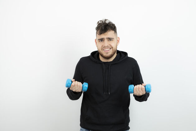 运动员年轻的运动员用蓝色的哑铃训练男人锻炼男