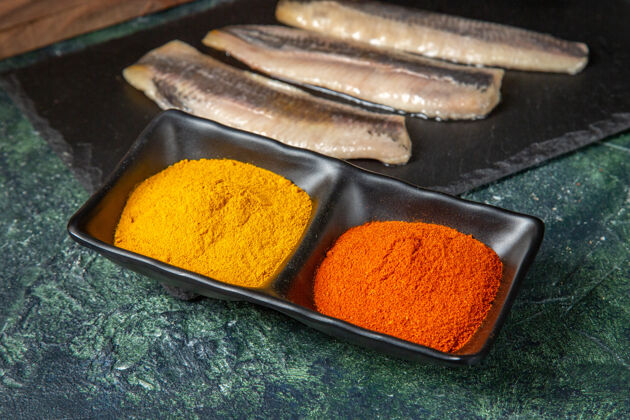 干果特写镜头新鲜的生切碎的鱼在黑色木砧板香料混合颜色的表面姜黄切割早餐