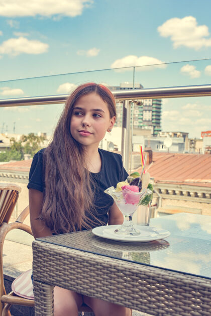 美丽少女开心地微笑着坐在餐厅或咖啡馆吃冰cream.food甜点女孩咖啡厅露台休闲甜点