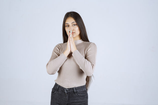 成人穿灰色衬衫的女孩双手合十祈祷聪明姿势服装