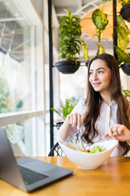 电脑在咖啡厅吃早餐时 身着休闲服 端着咖啡和沙拉的微笑女人的画像智能说话技术