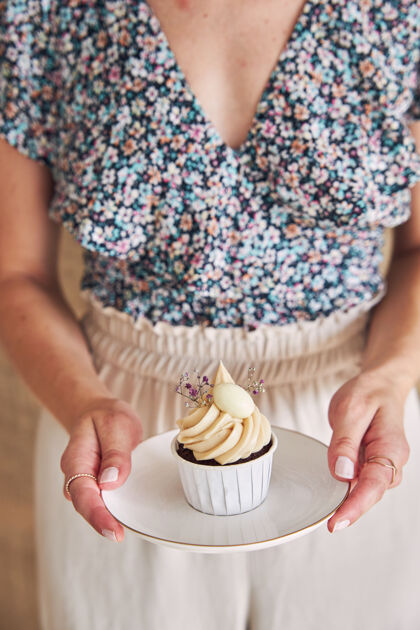 盘子选择性聚焦拍摄一个女人拿着美味的巧克力蛋糕和白色奶油顶巧克力糕点小