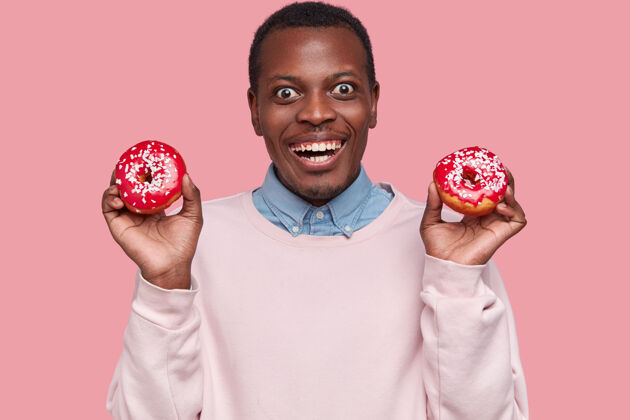 男性年轻的非洲裔美国人拿着美味的甜甜圈年轻男人成人