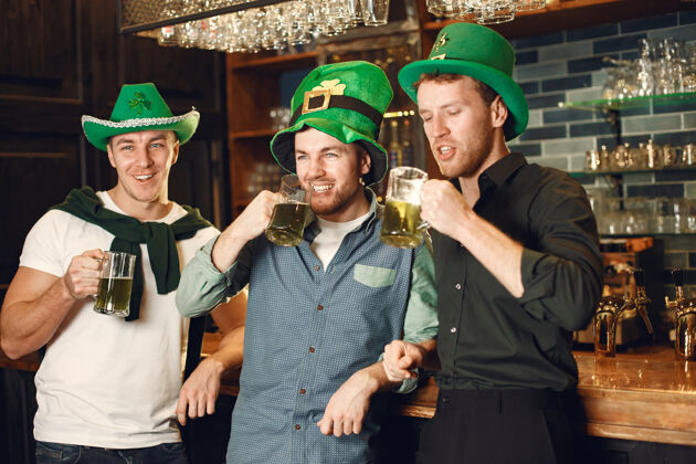 酒吧戴绿帽子的男人朋友们庆祝圣帕特里克节在酒吧庆祝爱尔兰聚会马克杯