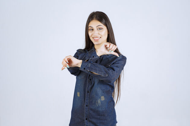 模特穿着牛仔衬衫的年轻女子 展示拇指朝下的标志讨厌不同意聪明