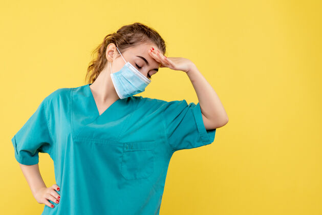 面具正面图身着医用衬衫和无菌口罩的女医生在黄色办公桌上大流行的彩色卫生制服covid-19病毒医疗黄色大流行
