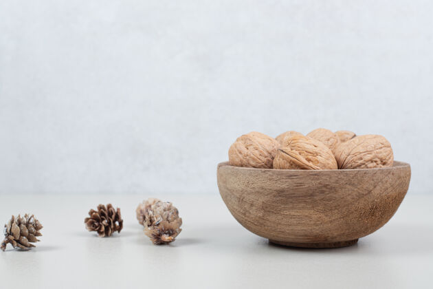 坚果一碗核桃和松果放在米色的表面核桃碗木材