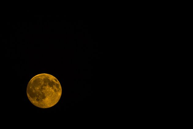 自然橘色的月亮在夜晚孤零零的一片黑色血液明亮轨道