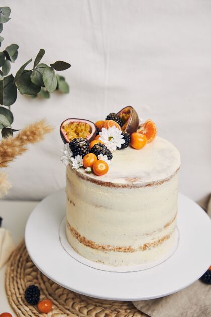 奶油白色的蛋糕和浆果和西番莲紧挨着一棵植物 背景是白色的奶油热带芝士蛋糕