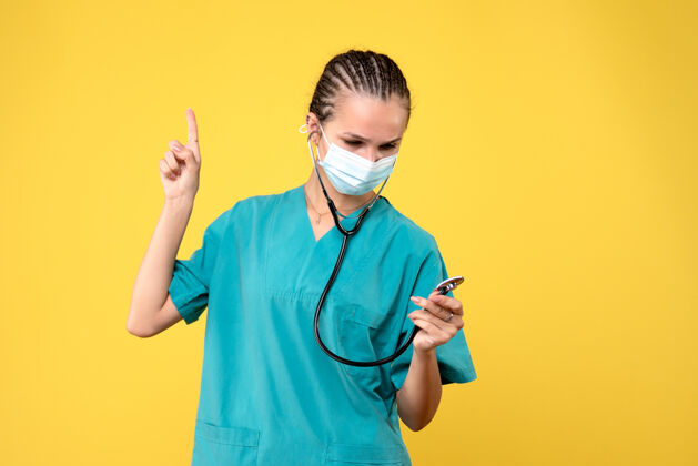口罩黄墙上穿着医疗服 戴着无菌口罩的女医生的正面图医院前台消毒