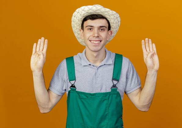 园艺微笑的年轻男园丁戴着园艺帽 用八个手指做手势佩戴微笑男性