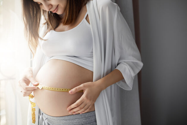 期望孕妇测量肚子的特写镜头 记录孩子的发育情况快乐妈妈关心健康怀孕休息成人新