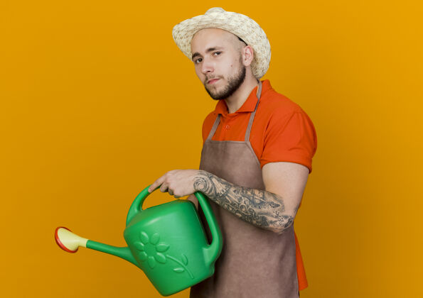 橙色自信的园丁戴着园艺帽拿着浇水罐浇水持有穿着