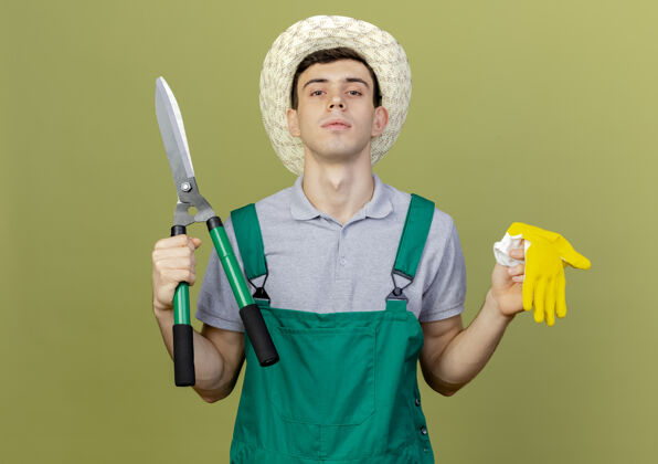 复制自信的年轻男园丁戴着园艺帽拿着剪刀和手套年轻园艺穿