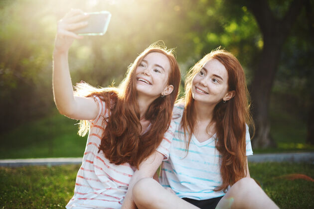 两个金杰双胞胎女孩在智能手机上自拍 开心地微笑着现代科技比以往任何时候都更能把人们联系在一起拥有一个远方的朋友真是太有趣了友谊成人长