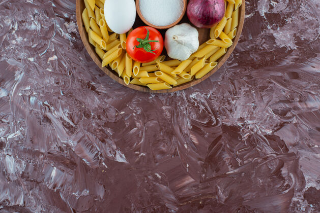 通心粉在大理石表面放一块生鸡蛋和蔬菜的木板意大利面柠檬料理