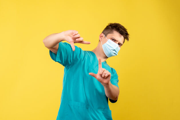 成人黄墙上带无菌口罩的男医生的前视图正面人手持