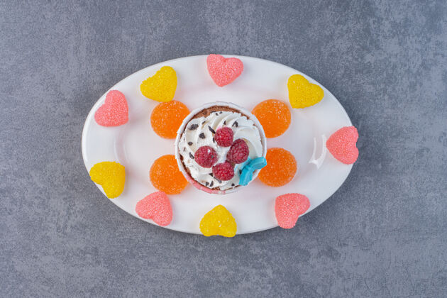 水果白色盘子上装饰着奶油和覆盆子的美味纸杯蛋糕糖果糖果杯子蛋糕