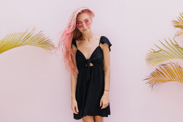 装束一个长着粉红色头发的女人站在工作室里奇异的棕榈树旁寒冷搞笑配饰
