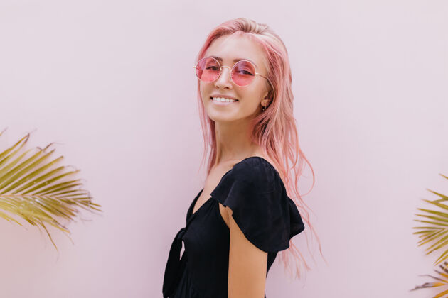 女人一个长着粉红色头发的女人站在工作室里奇异的棕榈树旁表情享受搞笑