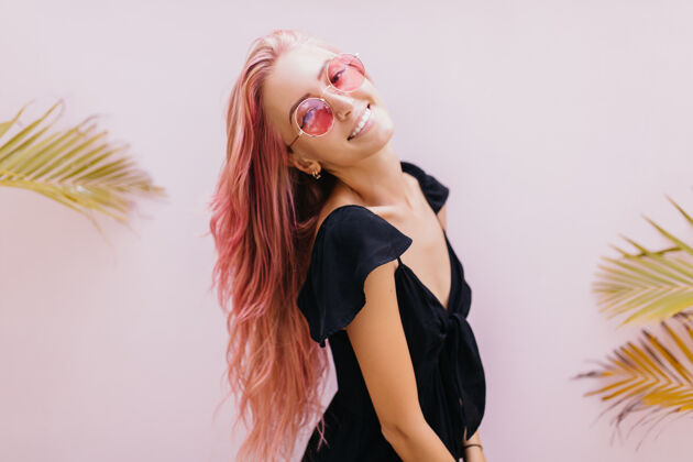 金发一个长着粉红色头发的女人站在工作室里奇异的棕榈树旁搞笑情感浪漫
