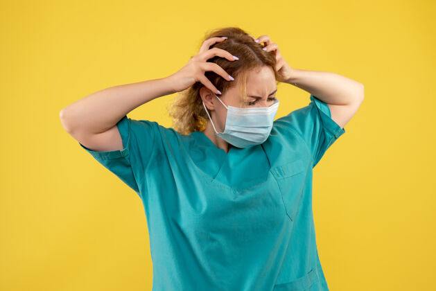 人黄墙上年轻女医生穿着医疗服 戴着口罩的正面图年轻女医生成人人
