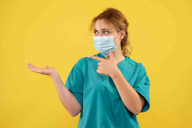 医疗黄墙上年轻女医生穿着医疗服 戴着口罩的正面图成人健康面具