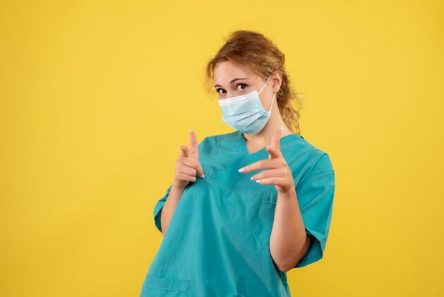 人物黄墙上穿着医疗服 戴着无菌口罩的女医生的正面图面具面部护士