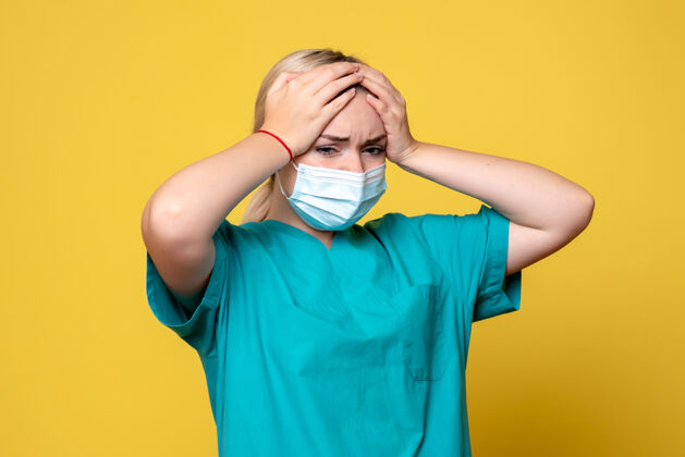 衬衫黄色墙上穿着医用衬衫和无菌口罩的年轻女医生的正视图医疗绝育护士