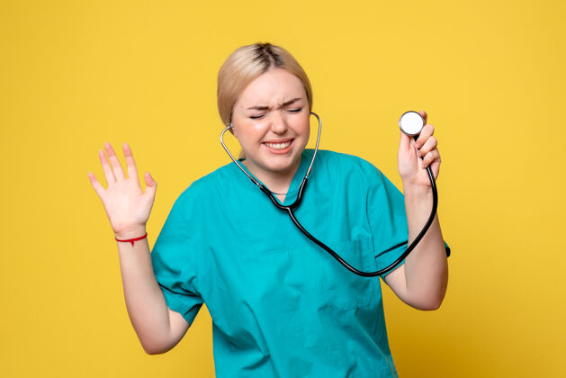 人黄色墙壁上穿着带听诊器的医用衬衫的女医生的正视图听诊器医疗微笑